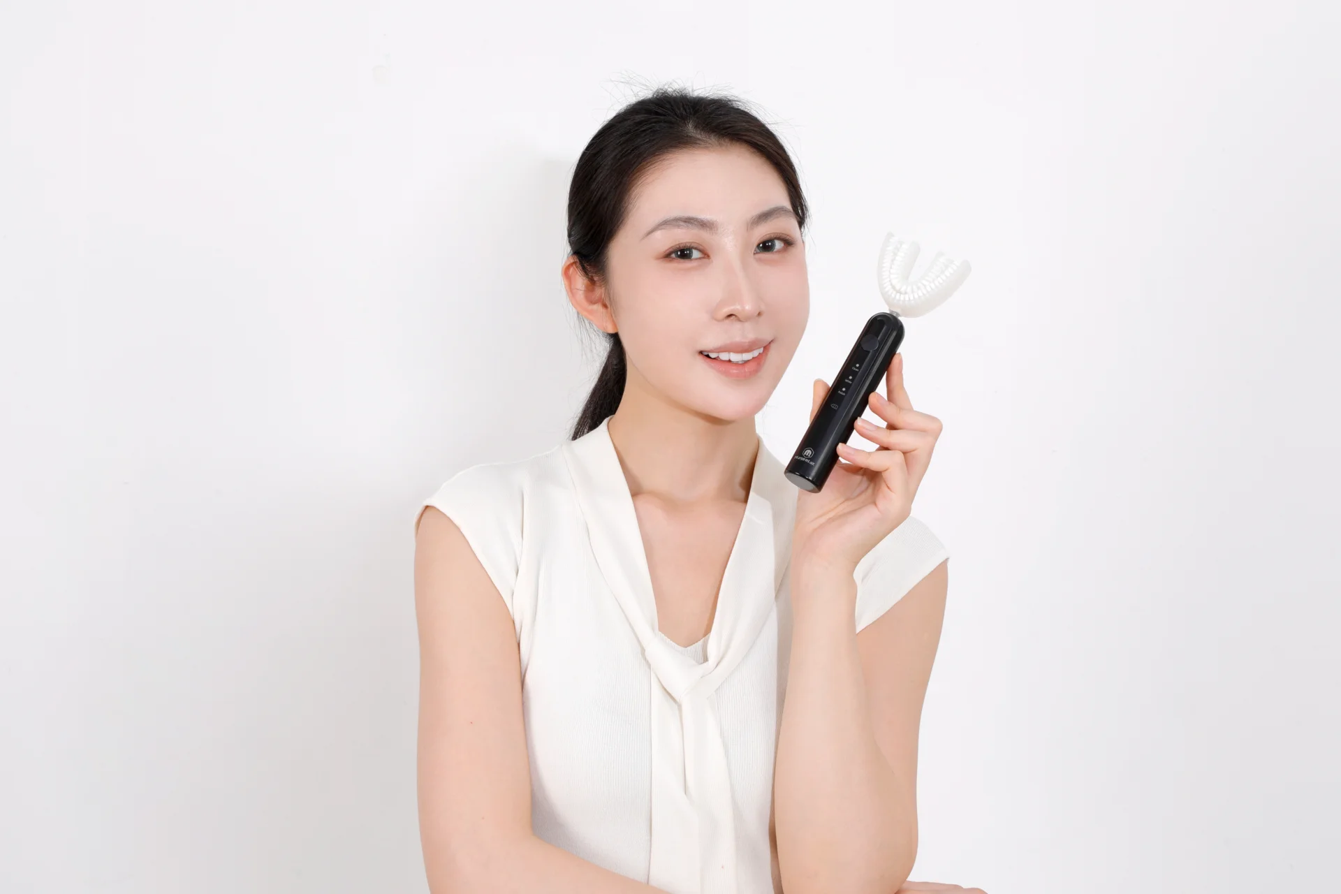 Black TB-03 toothbrush held beside the face, with the complete head and handle visible